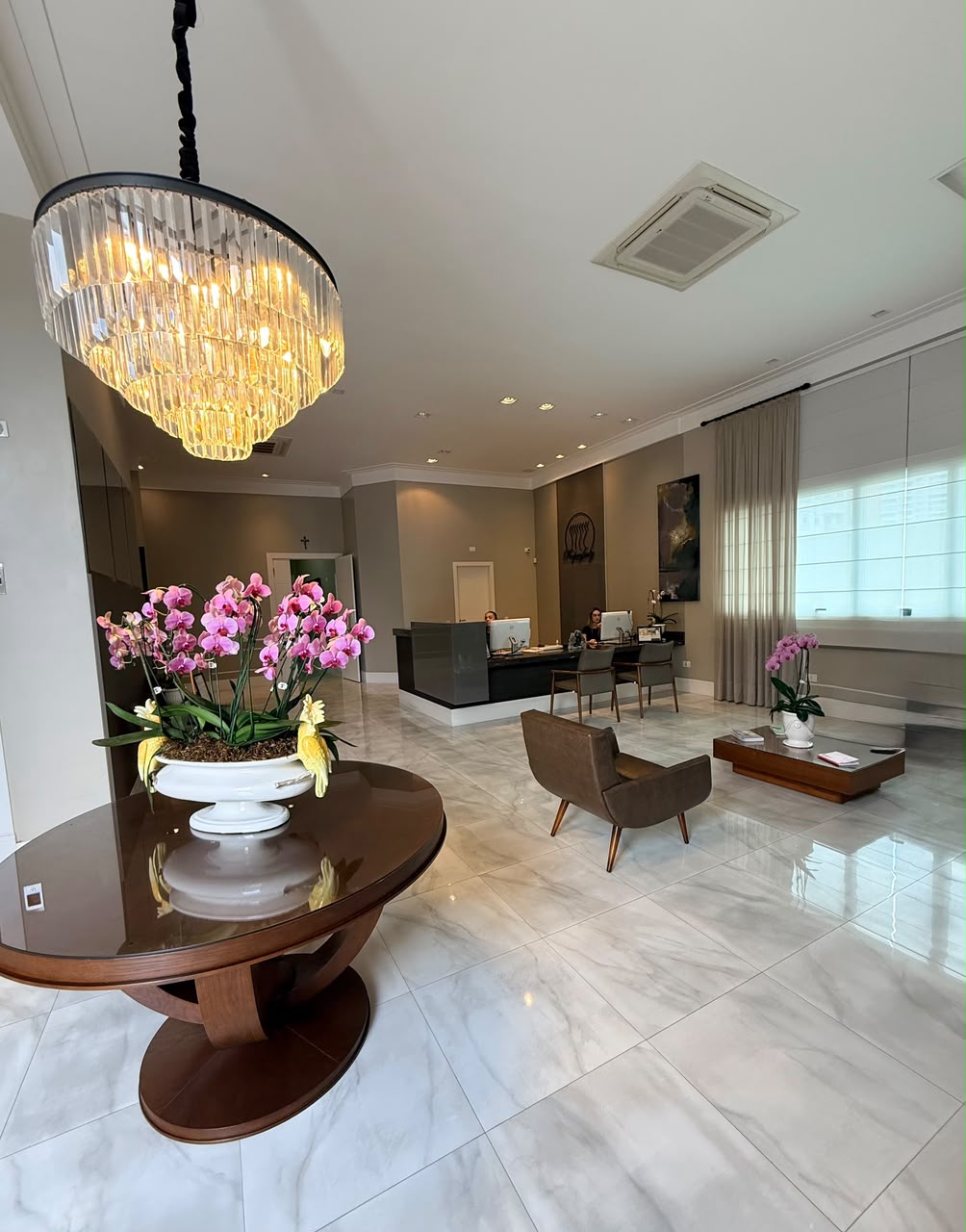 Recepção da clínica Reproferty com lustre e mesa de orquídeas